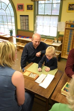 A child learning with assistance from a teacher from the programs at Country Village Montessori School