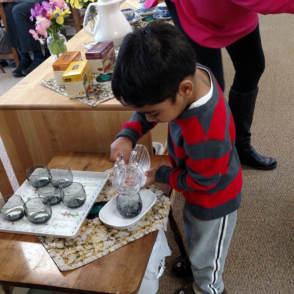 A student at the children's house pouring water in cup